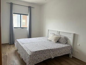 A bedroom with a single bed, a window with curtains, and a wooden floor. - Perfect 3-bedroom apartment in Praia for a relaxing getaway (Praia)