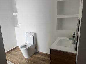 A bathroom with a toilet, a sink, and a mirror. - Perfect 3-bedroom apartment in Praia for a relaxing getaway (Praia)