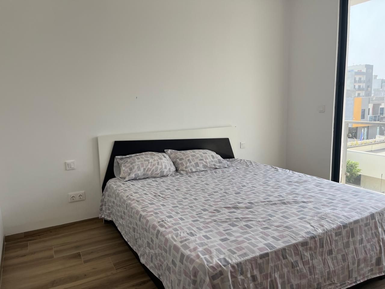 Un dormitorio con una cama, una ventana y vistas a edificios.
