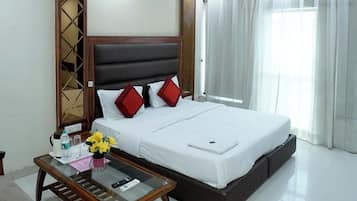 Una habitación de hotel con una cama, una mesita de noche, una silla, un ventilador de techo y una ventana con cortinas.