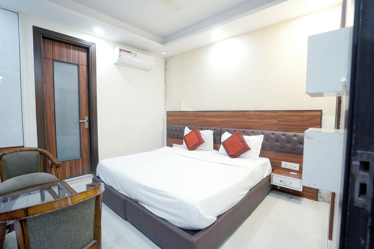A hotel room with a bed, a chair, a desk, and a wardrobe.