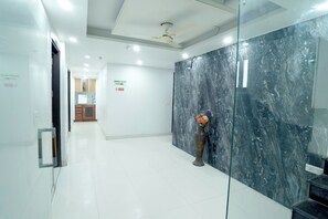 A clean, modern lobby with a marble wall, a reception desk, and a vase with flowers.
