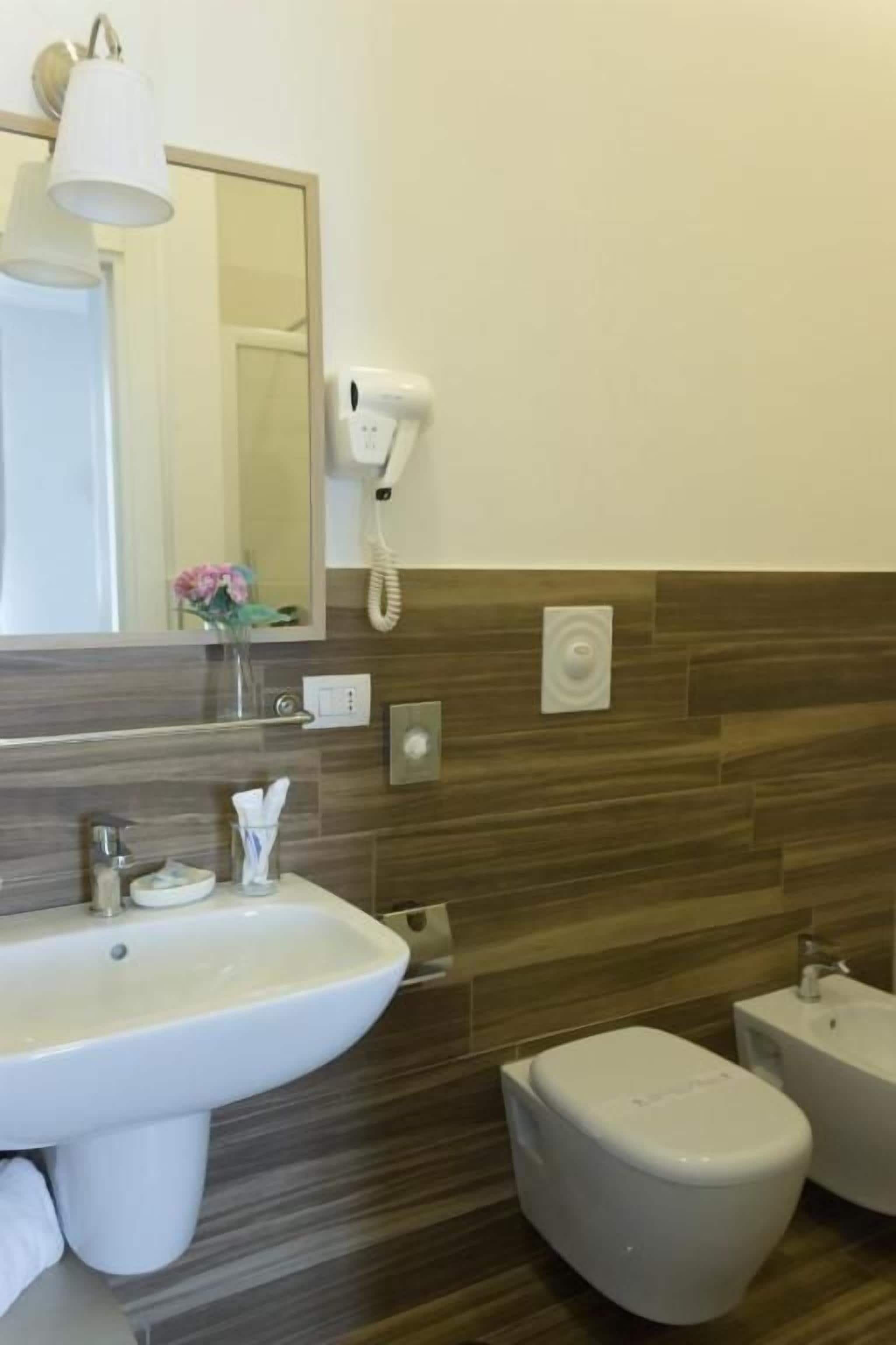 A bathroom with a sink, toilet, and a hairdryer mounted on the wall.