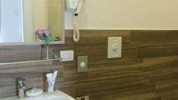 A bathroom with a sink, toilet, and a hairdryer mounted on the wall.