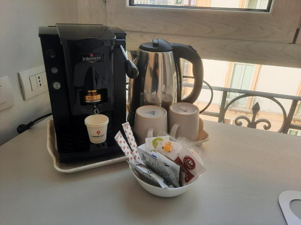 A coffee machine, two cups, and a bowl of coffee pods on a table.