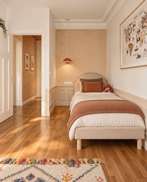 Ein Schlafzimmer mit einem großen Bett, einem Nachttisch, einer Pendelleuchte und einem farbenfrohen Teppich.