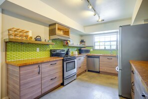 Eine moderne Küche mit Holzschränken, einem Edelstahlkühlschrank, einer Mikrowelle und einem Herd.