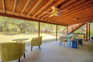 An outdoor covered patio with wooden beams, a ceiling fan, and seating arrangements including tables and chairs. - 9 Mi to Six Flags! Wooded Retreat w/ Patio (San Antonio)