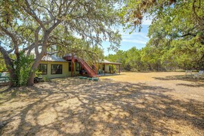 A house with a covered porch, a staircase, and a fenced yard. - 9 Mi to Six Flags! Wooded Retreat w/ Patio (San Antonio)