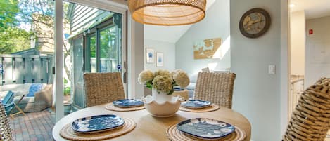 Een ronde eettafel met placemats en een bloevas, omringd door rieten stoelen.