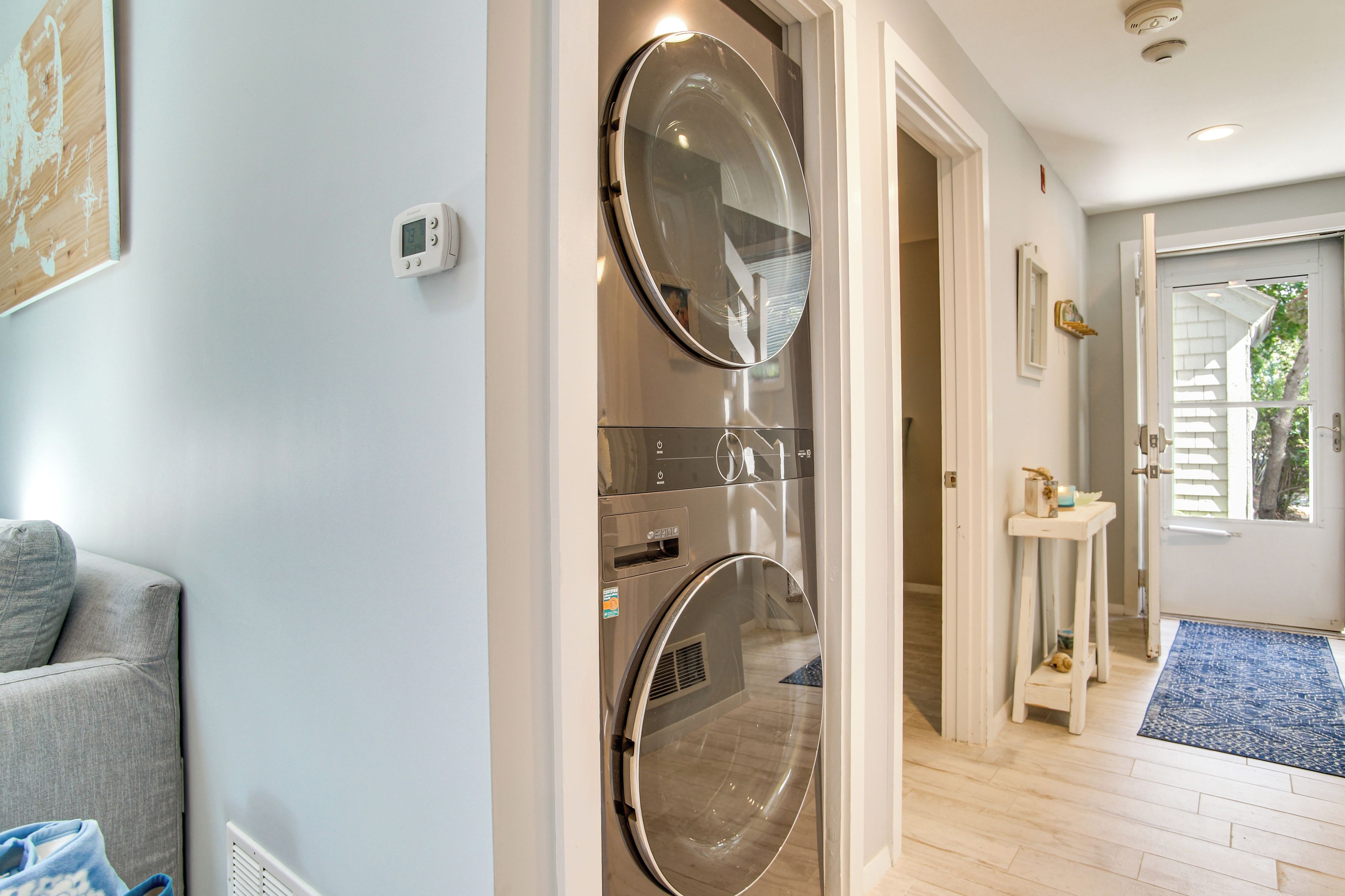 A laundry room with two front-loading washing machines, a small table with a candle, and a door leading to a hallway.