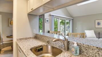 A kitchen with granite countertops, a stainless steel sink, and a view of the outdoor patio.