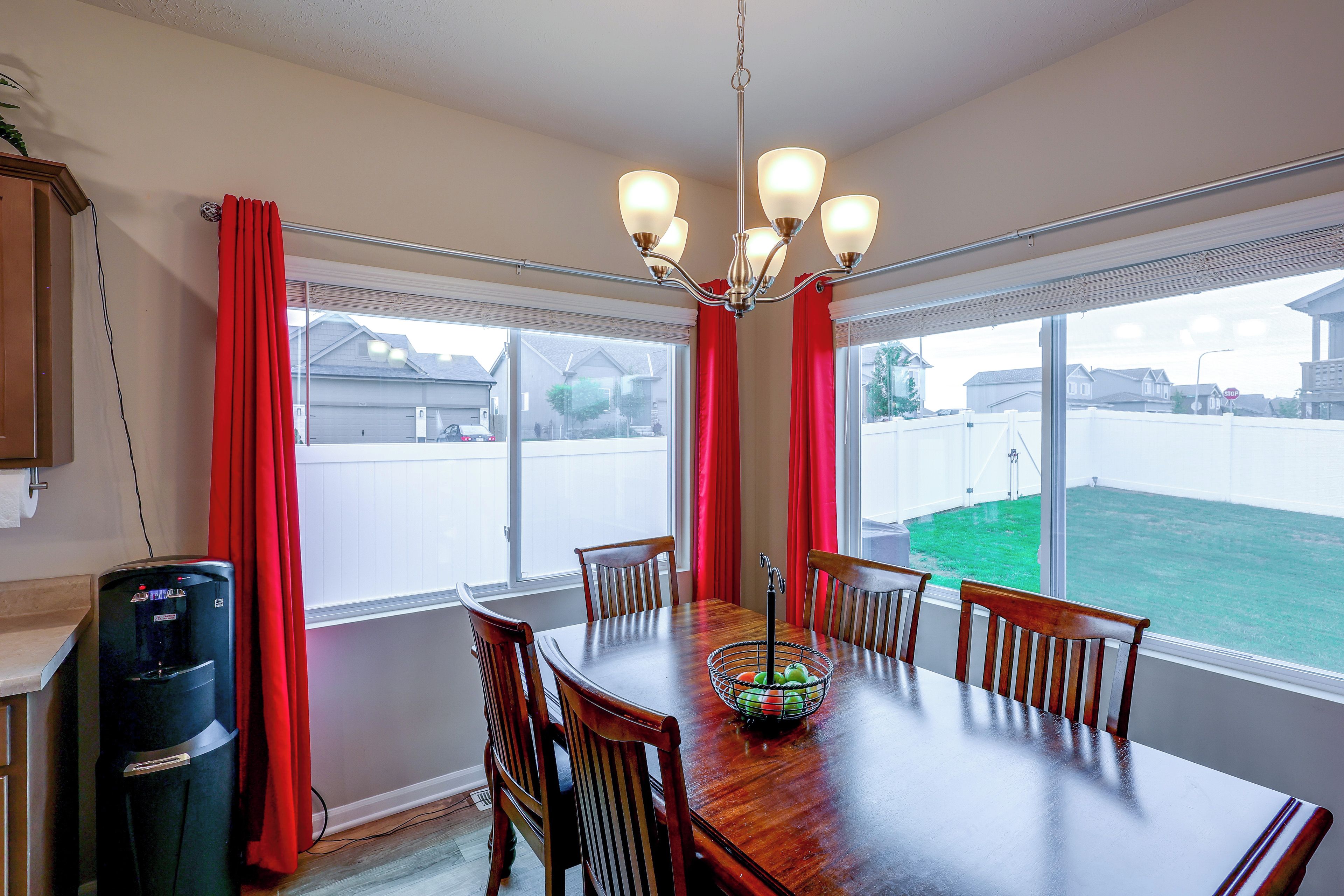 A dining room with a wooden table, red curtains, and a chandelier.