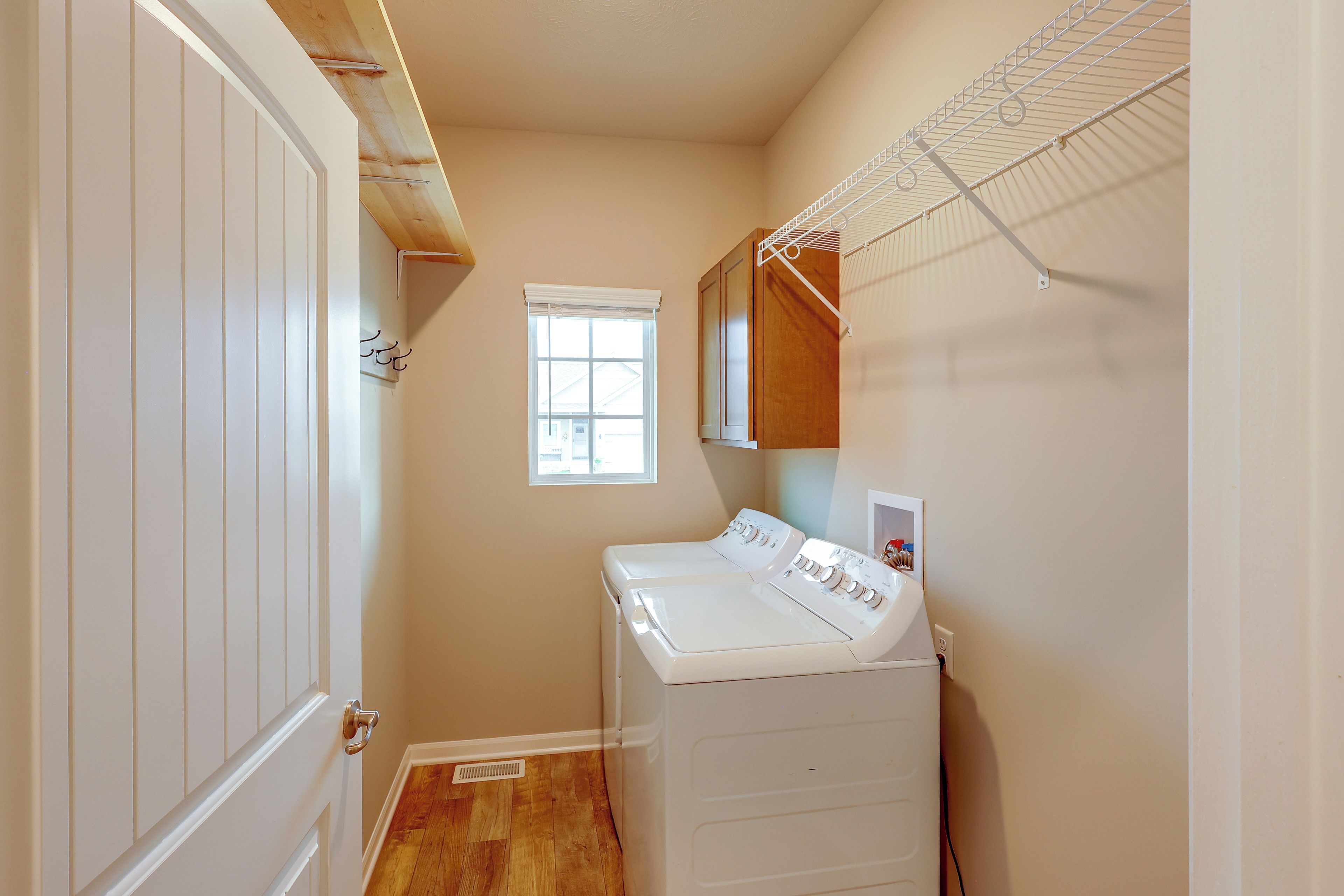 A laundry room with a washing machine and dryer, a window, and a door.