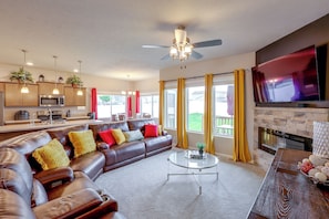 A modern living room with a leather sofa, a glass coffee table, and a flat-screen TV mounted on the wall.