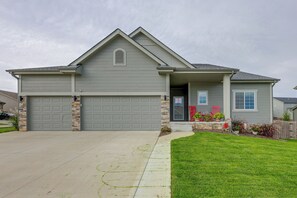 A two-story house with a garage, a front porch with potted plants, and a well-maintained lawn.