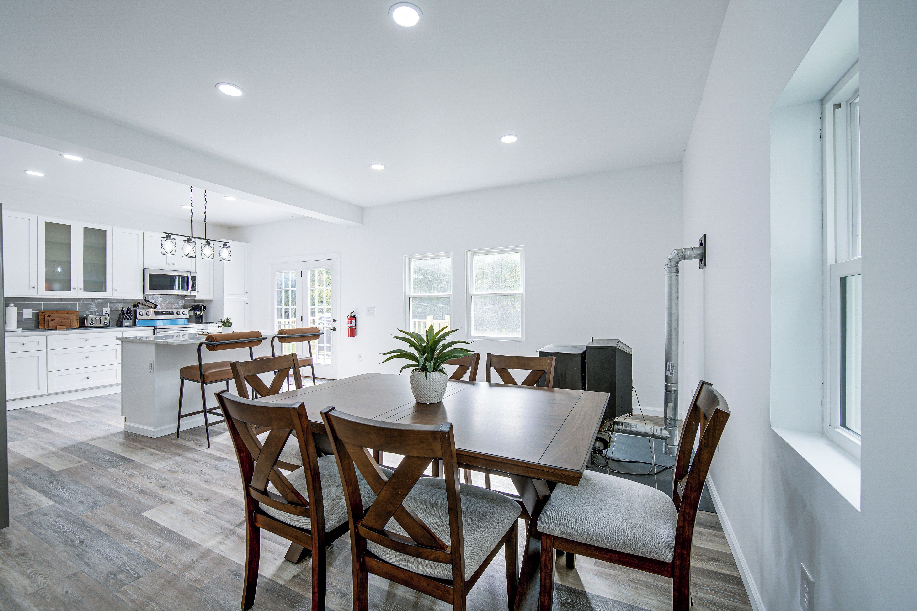 Una cocina moderna con armarios blancos, una isla central y un comedor con sillas de madera y una mesa.