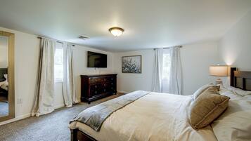 A bedroom with a bed, a dresser, a television, and a painting on the wall.