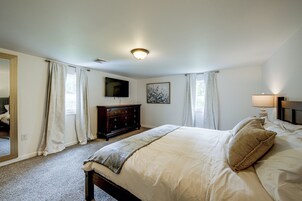 A bedroom with a bed, a dresser, a television, and a painting on the wall.