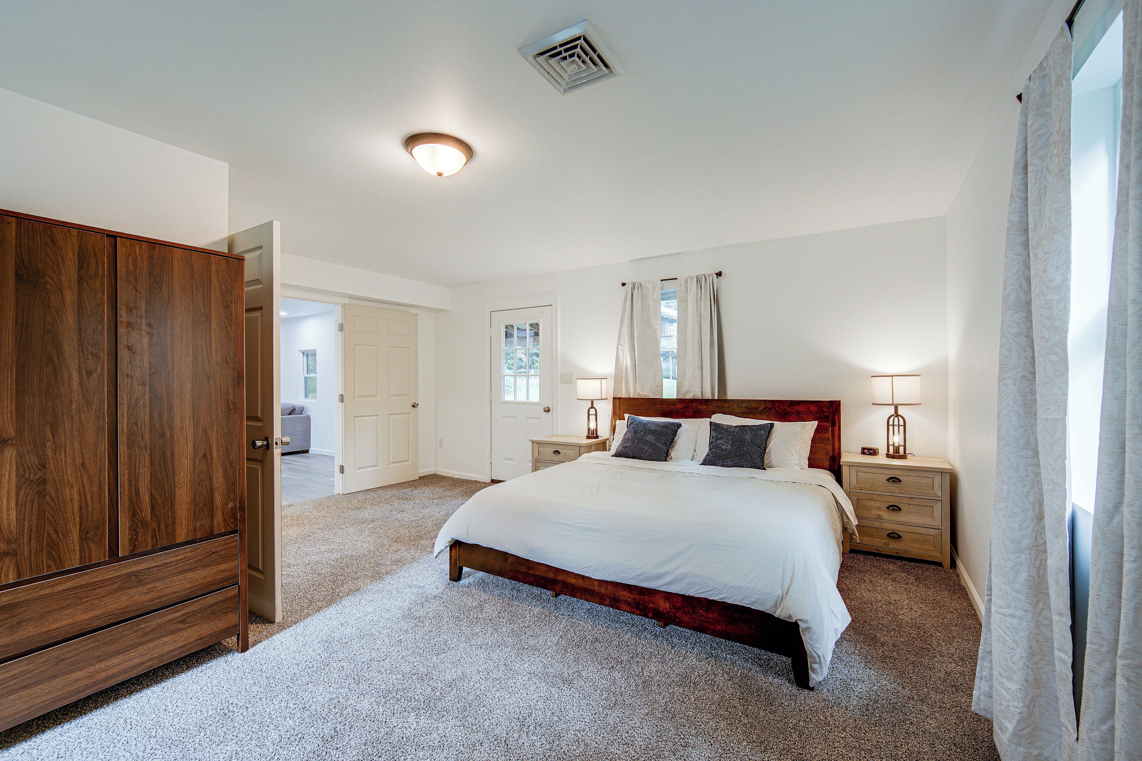 A bedroom with a bed, nightstands, a wardrobe, and a door leading to another room.