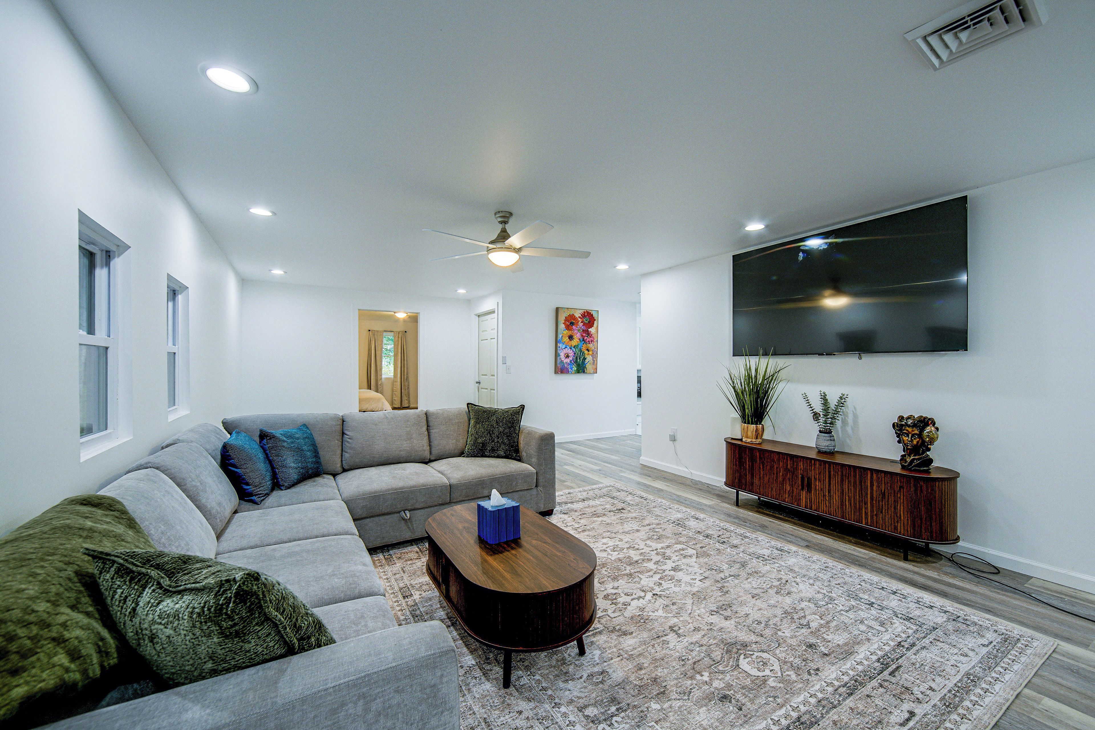 A modern living room with a sectional sofa, a coffee table, a flat-screen TV, and a decorative plant.