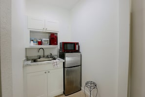 A compact kitchenette with a stainless steel refrigerator, a red microwave, a sink, and a small table. - 2 Mi to Universal Orlando! Quiet Studio Suite (Orlando)