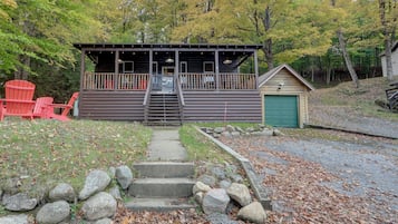A cabin with a porch, a small garage, and a set of stairs leading to the entrance.
