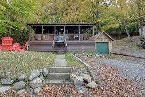 A cabin with a porch, a small garage, and a set of stairs leading to the entrance. - Old Forge Winter Escape: Snowmobile & Ski! (Old Forge)