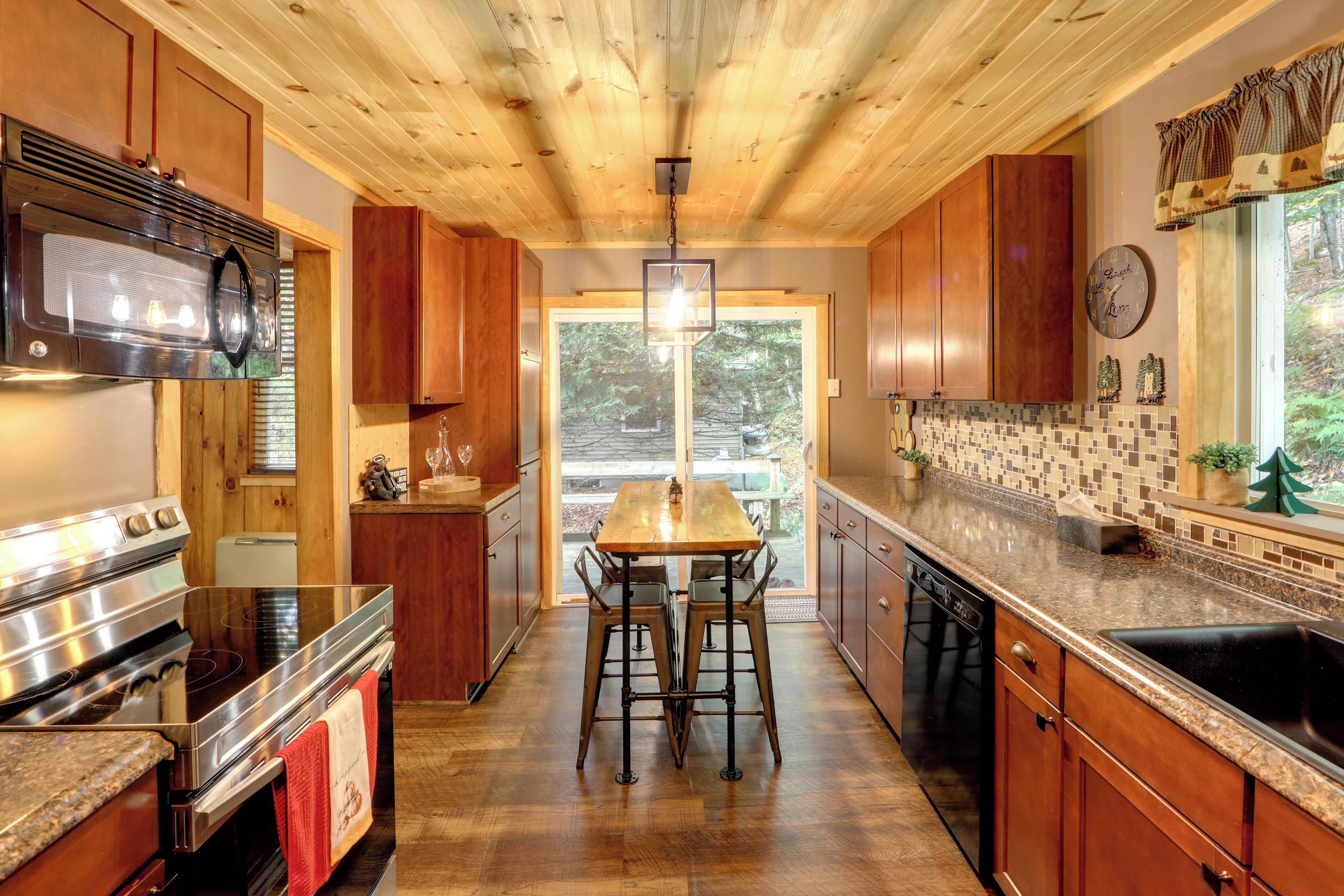 A kitchen with wooden cabinets, a stainless steel range, and a dining area with a table and chairs.