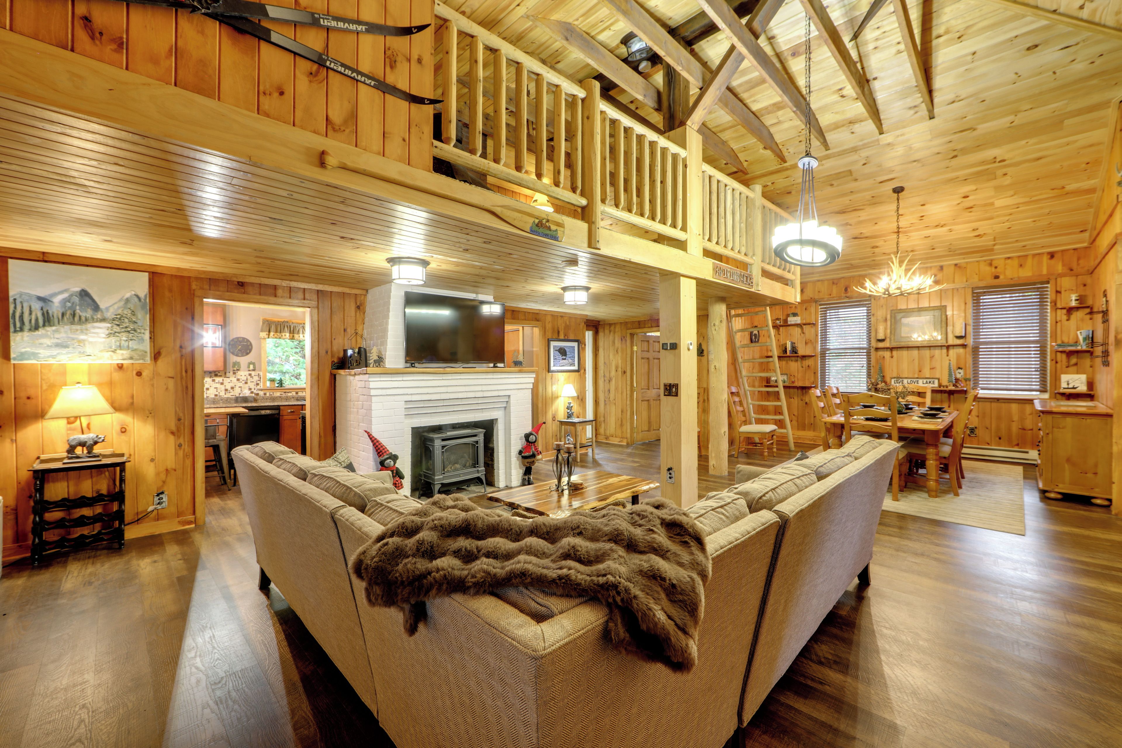 A spacious living room with a fireplace, a dining area, and a kitchen.