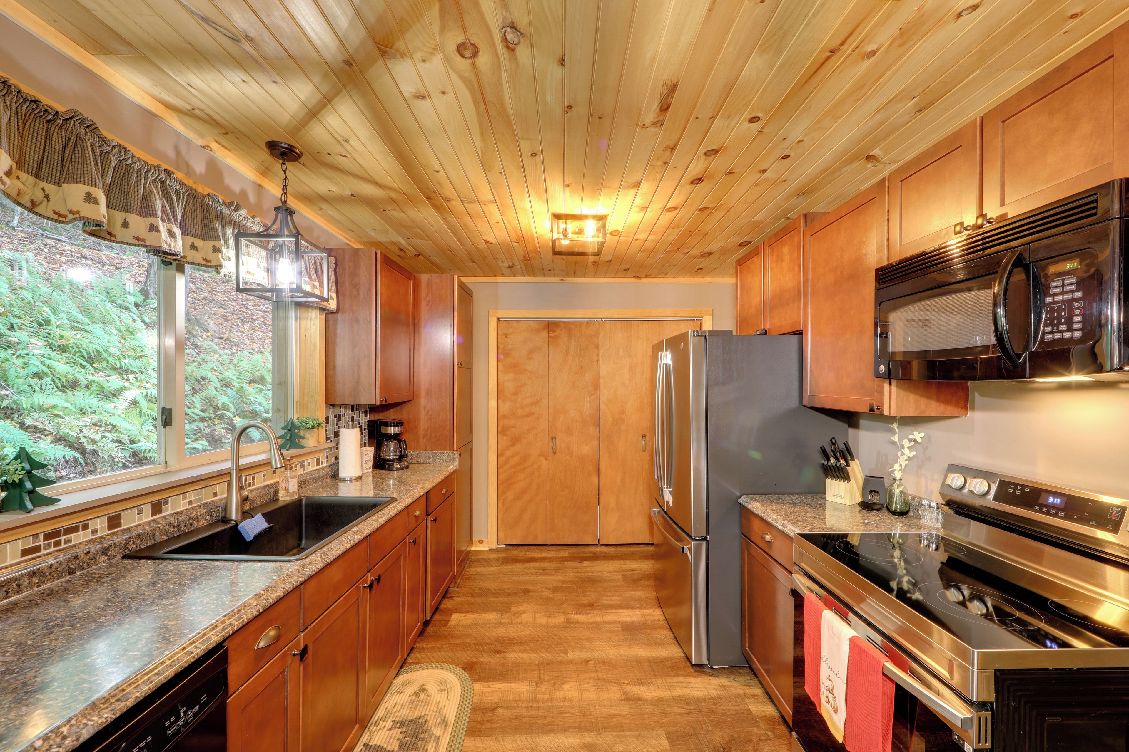 A kitchen with wooden cabinets, stainless steel appliances, a granite countertop, and a view of the outdoors.