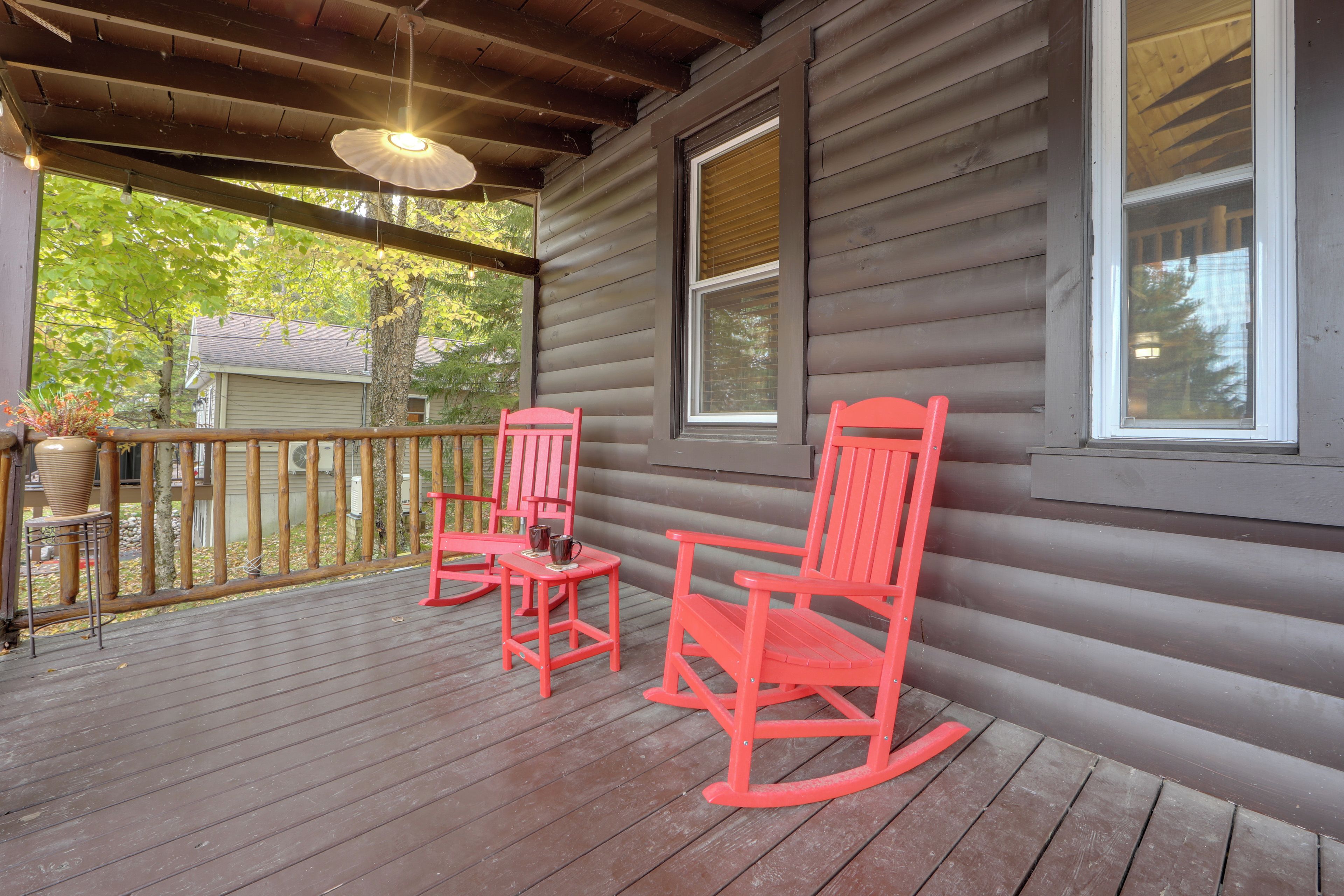 A wooden porch with two rocking chairs and a table, overlooking a green landscape.