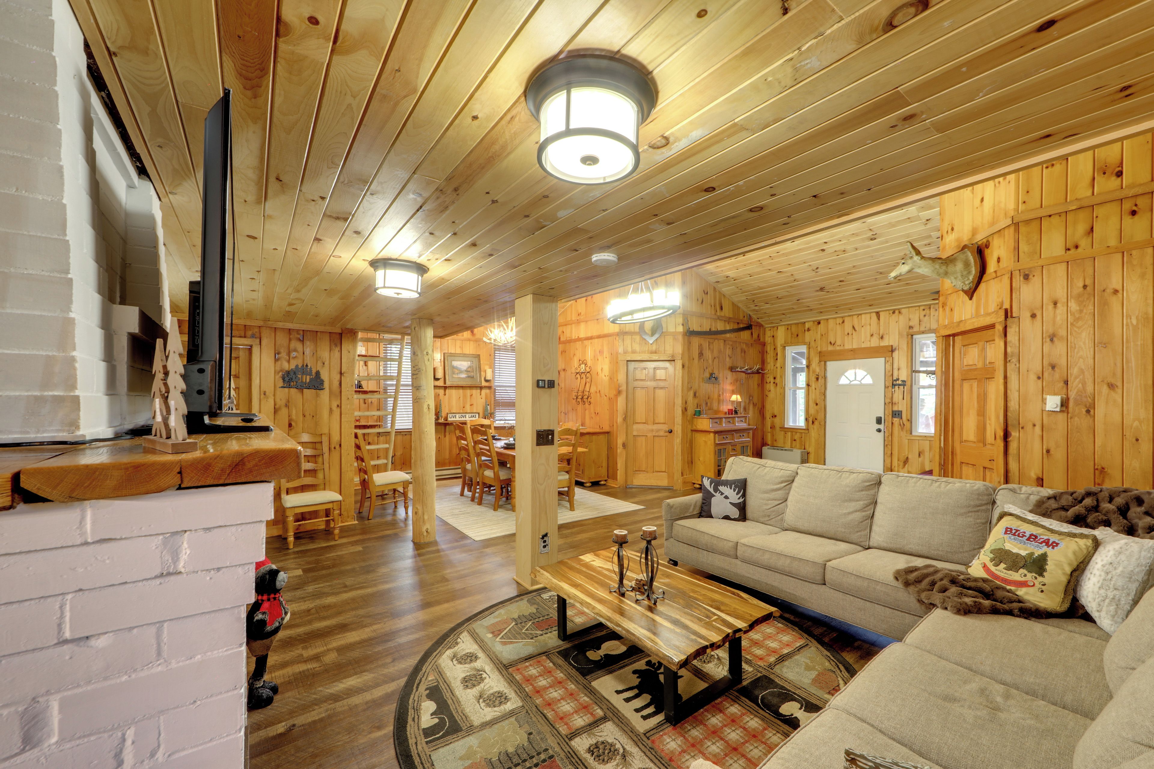 A cozy cabin interior with a wooden interior, a sofa, a coffee table, and a fireplace.