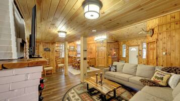 A cozy cabin interior with a wooden interior, a sofa, a coffee table, and a fireplace.