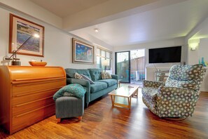 A living room with a sofa, armchair, coffee table, wooden cabinet, and artwork on the walls. - Walk to Downtown Edmonds! Condo w/ Patio (Edmonds)