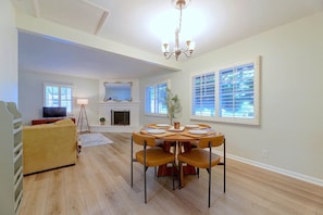 A spacious living area with a dining table set for four, a fireplace, and a television in the background. - 1 Mi to Dtwn Downey + Fenced Yard! (Downey)