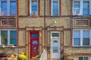 A multi-story brick building with a red door, white door, and multiple windows. - Gateway to Nyc! Modern & Cozy Unit (Bayonne)