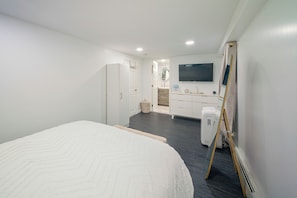 A bedroom with a bed, a dresser, a television, and a mirror. - Gateway to Nyc! Modern & Cozy Unit (Bayonne)