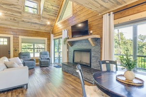 Un amplio salón con chimenea, asientos y ventanas grandes.