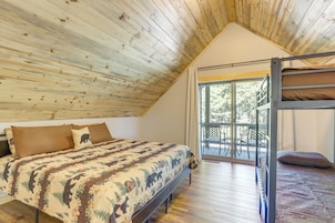 Un dormitorio con una cama litera, un ventanal grande y techo de madera.