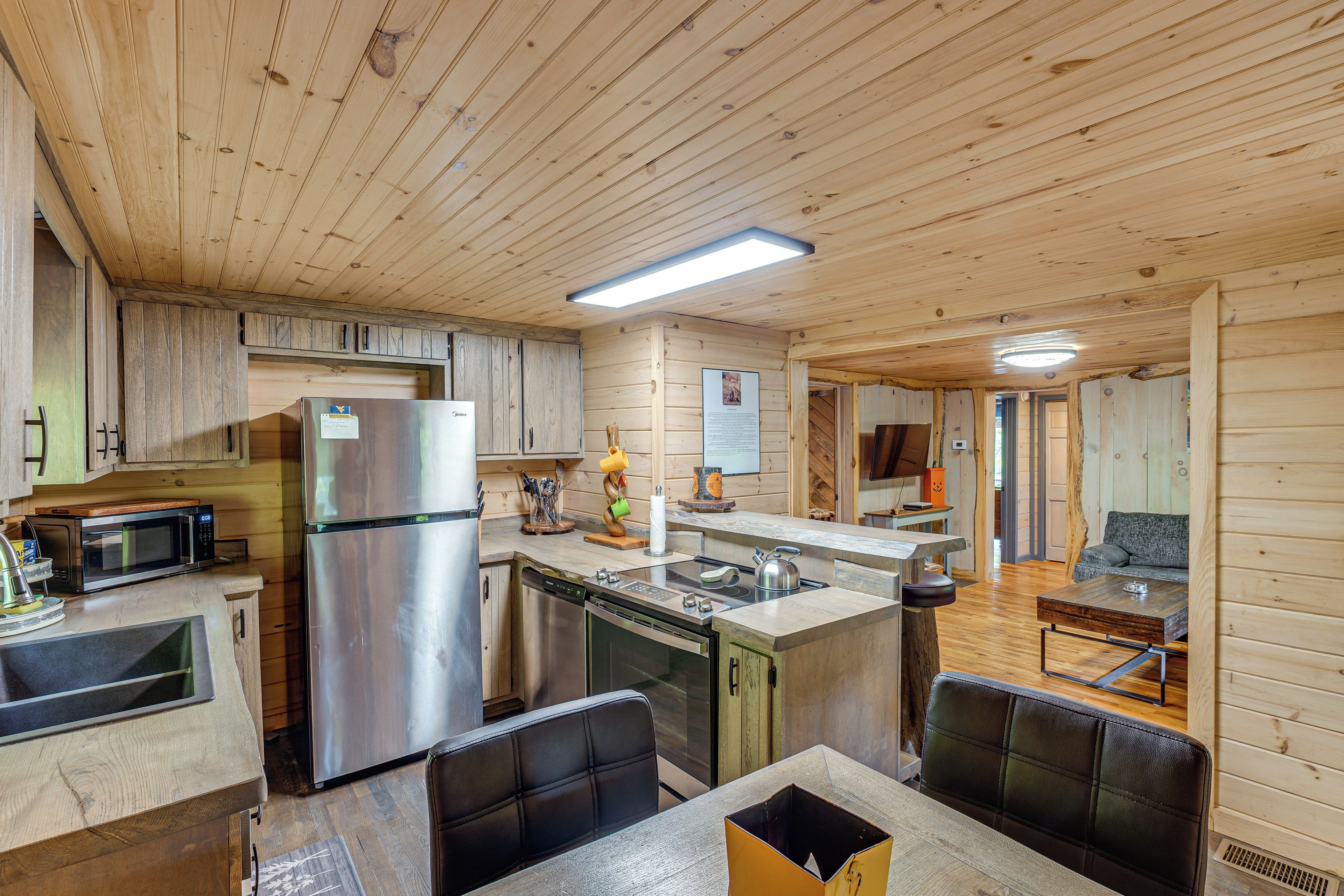 A wooden interior with a kitchen area featuring a refrigerator, microwave, and stove.