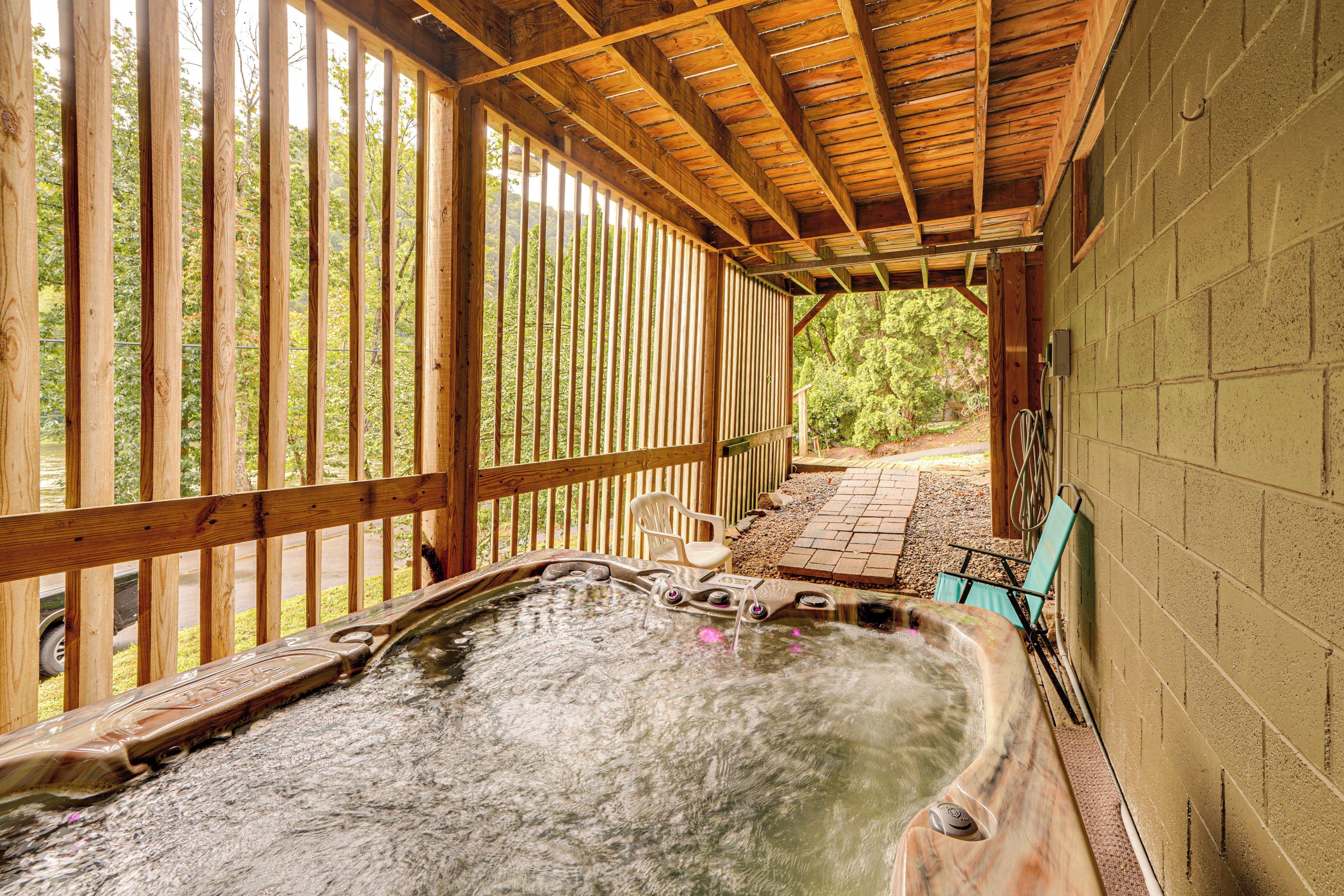 A hot tub area with wooden railings, a brick pathway, and a view of trees.