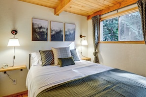 A bedroom with a bed, two bedside tables, a window with curtains, and three framed pictures on the wall. - Lake Cushman Cabin - Hike, Swim, Golf, Relax (Hoodsport)