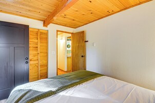 Una habitación con cama, techo de madera y puerta que da a un baño.