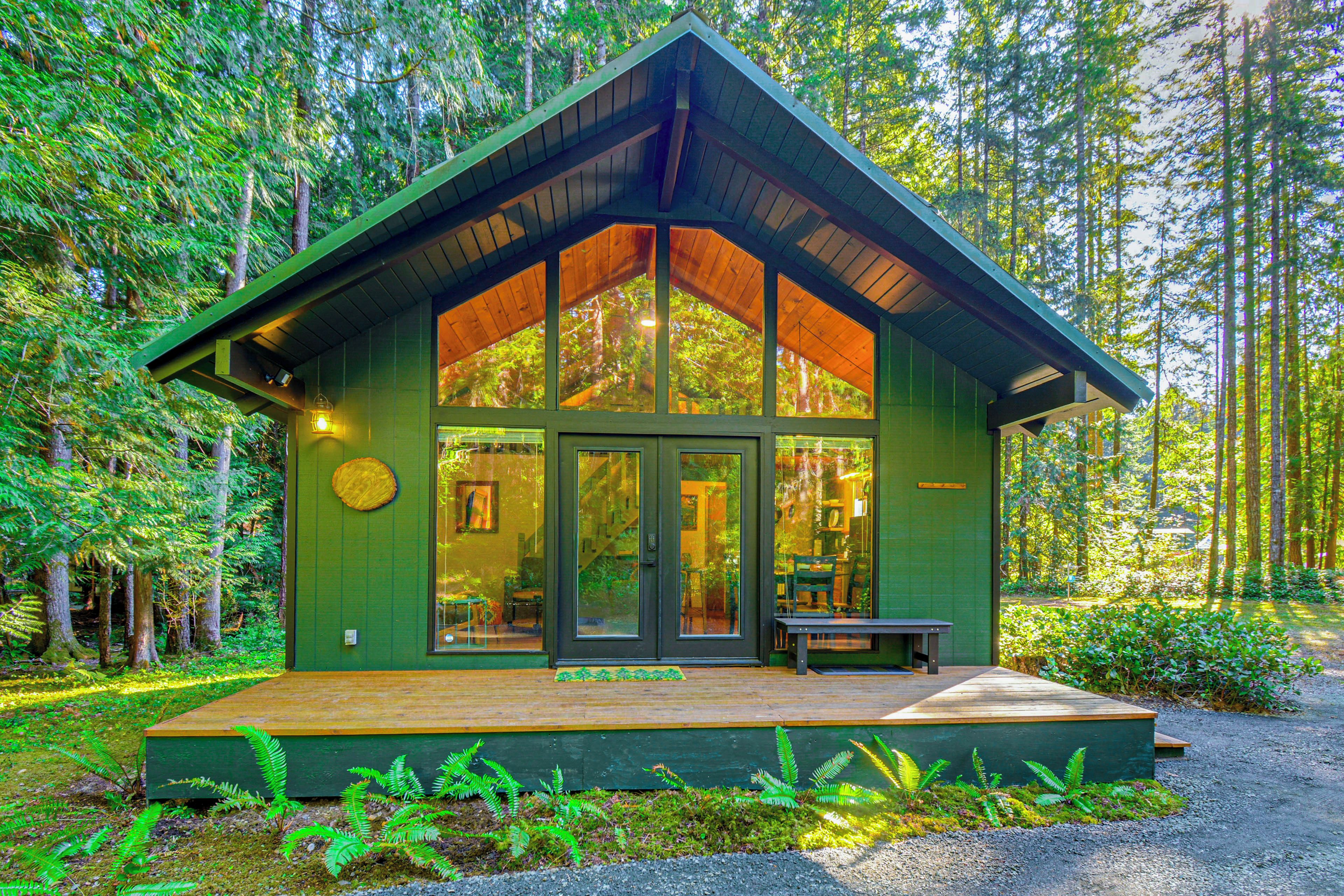 A cabin with a wooden deck, large windows, and a door.