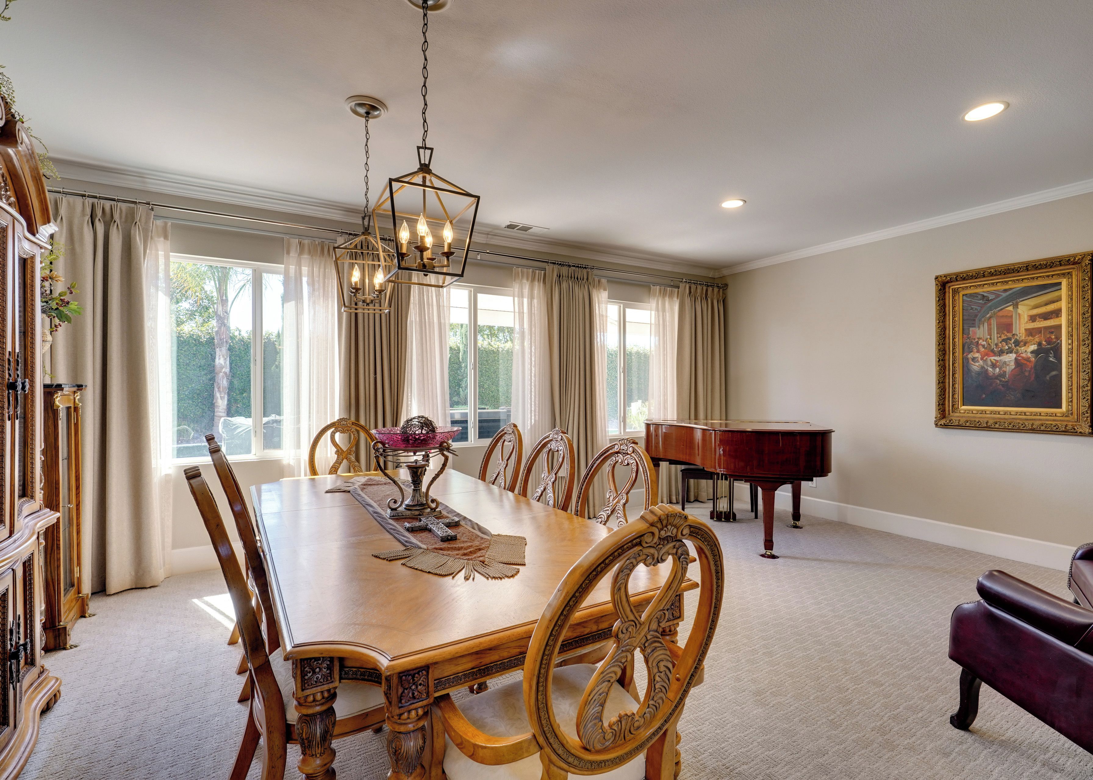 A dining room with a wooden table, chairs, a piano, and a painting on the wall.
