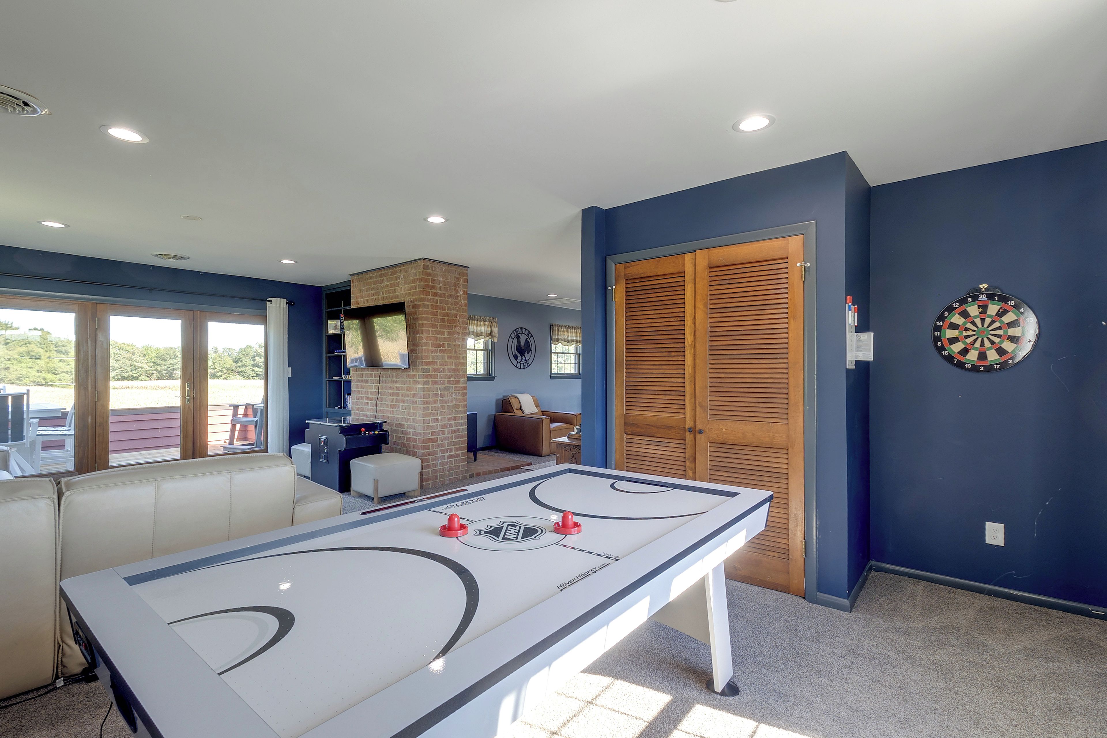 A room with a foosball table, a dartboard, and a pool table.