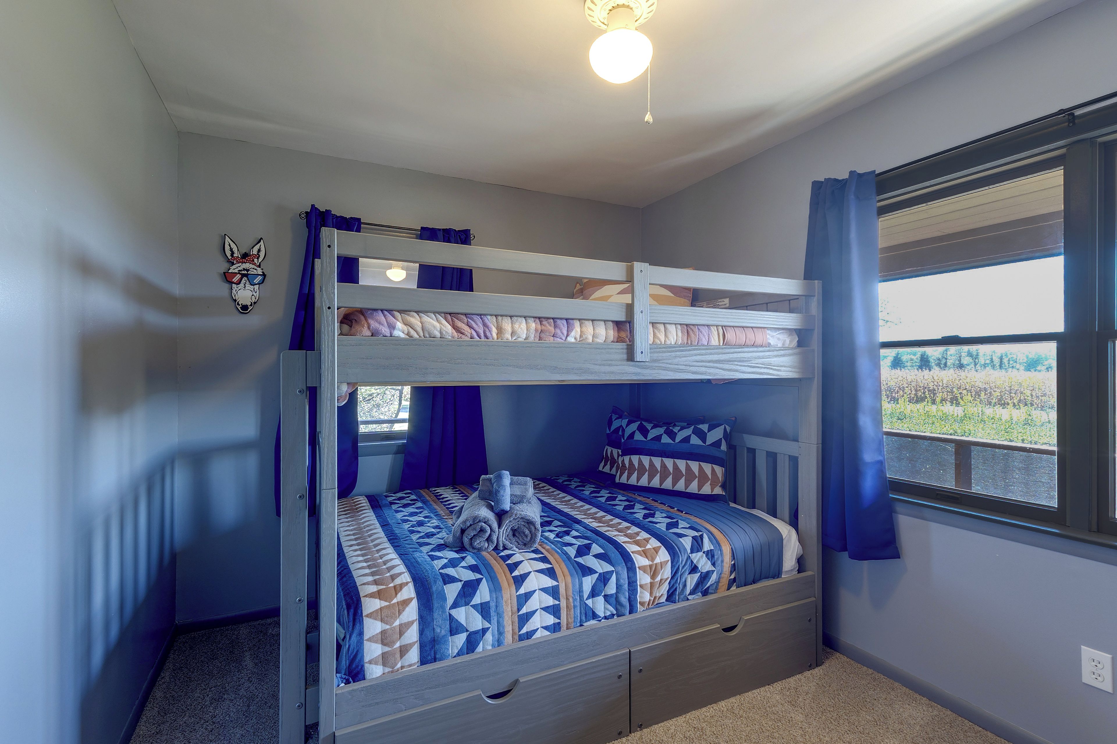 A bunk bed room with a view of the outdoors through a window.