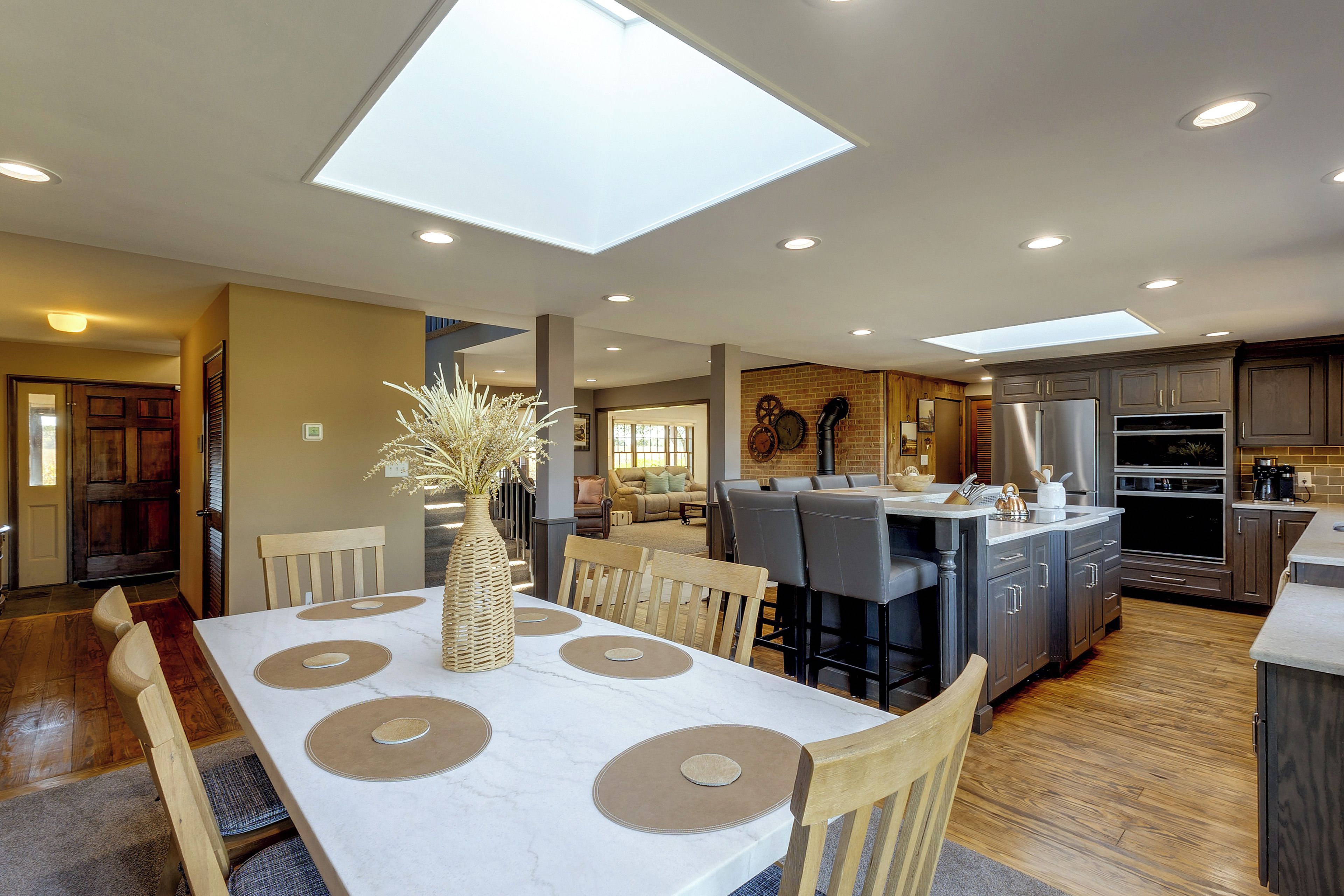 A modern kitchen with a central island, recessed lighting, and a dining area with a table set for four.