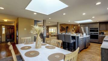A modern kitchen with a central island, recessed lighting, and a dining area with a table set for four.